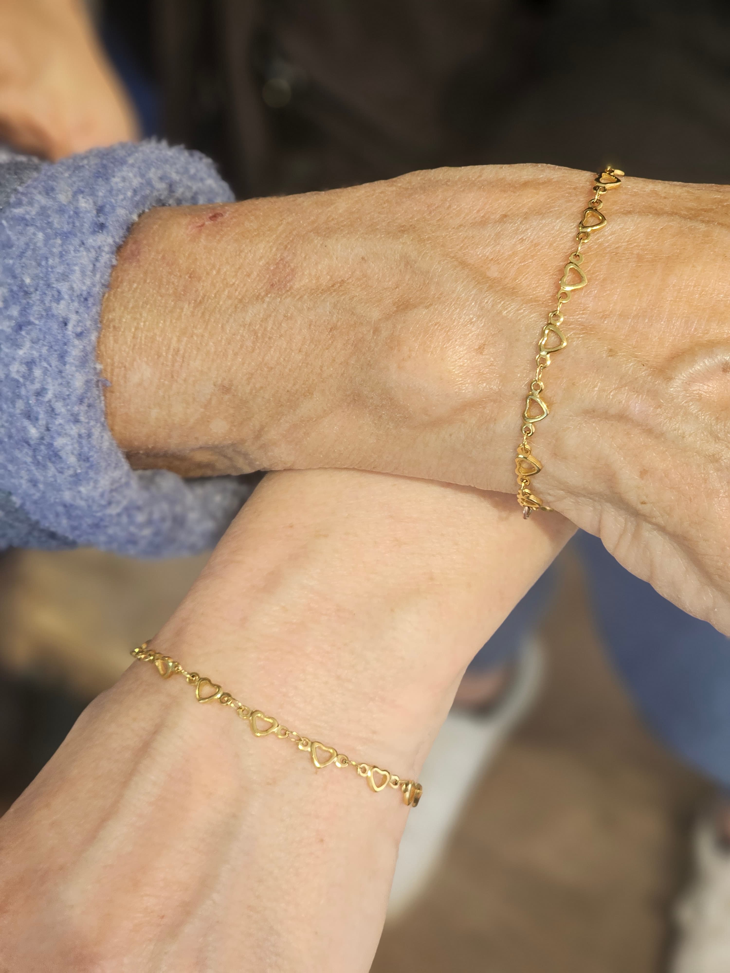 Two generations wearing matching permanent gold heart bracelets